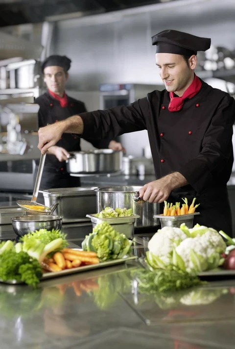 Kucharz w profesjonalnej kuchni przyrządza danie ze świeżych warzyw